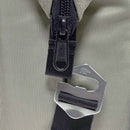 Close-up of a black zipper and silver metal bear logo clip on a black strap against textured gray fabric, highlighting the Polar Bear Coolers 12 Pack Original Nylon Soft Cooler—an insulated bag ideal for everyday use.