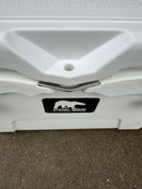 Close-up of the Polar Bear Coolers Polar Bear 20 Hard Cooler, featuring a white body, metal latch, and front logo label, set on a concrete surface.