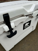Close-up of a Polar Bear 20 Hard Cooler by Polar Bear Coolers, featuring black latches and a bear logo on the front. This white hard cooler sits on a concrete surface and is engineered for superior ice retention.
