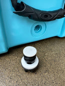 A close-up of the Polar Bear Coolers Polar Bear 45 Hard Cooler shows its black handle, drain hole, and white drain plug on textured concrete—ideal for long-lasting ice retention on outdoor adventures.