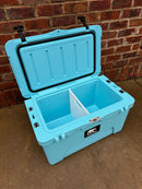 A Polar Bear Coolers 45 Hard Cooler in light blue, with a divider, sits open on concrete before a red brick wall. It features black latches, a front logo, and provides extended ice retention for outdoor adventures.