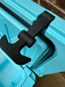 A close-up shows a black latch securing the lid of a bright blue Polar Bear 45 Hard Cooler by Polar Bear Coolers, partially open against a brick wall and concrete background, emphasizing this rugged outdoor cooler.