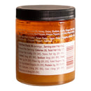A clear plastic jar of Spice Witch Chili Crisp Spicy Honey Flavor sits against a white background. The black lid tops the jar, and its label from Spice Witch shows ingredients and nutrition facts, with orange-brown crunchy paste inside.