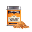 A Spicewalla Citrus & Sesame Everything Seasoning tin, with orange, black, and white label, is displayed with some of the citrus sesame seasoning blend spilled in front.