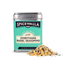 A tin of Spicewalla Everything Bagel Seasoning by Spicewalla is next to a pile of its savory blend with sesame seeds, poppy seeds, dried onion, and garlic.
