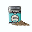 A tin of Spicewalla Green Cardamom Powder with a teal and black label sits beside a small mound of vibrant green powder, highlighting the fragrant spice on a white background.