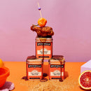 Spicewalla hot honey BBQ rub canisters with a chicken skewer on a pink and orange background