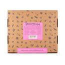 The Spicewalla Kitchen Essentials 18-Pack Collection features a brown box with spice illustrations, a pink label listing spices, and “Made with love in Asheville, NC”—a perfect starter set for your kitchen from Spicewalla.