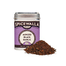 A tin of Spicewalla Minced Black Garlic by Spicewalla sits beside a mound of the rich umami seasoning, perfect for enhancing any dish, against a white background.