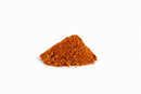 A small mound of reddish-brown Spicewalla Mom's Taco Seasoning is piled on a white background.
