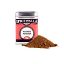 A small Spicewalla Nutmeg Powder tin stands behind loose brown nutmeg powder on a white background, showcasing this warming baking spice from Spicewalla.