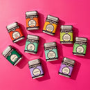 The Spicewalla Signature Blends 10-Pack by Spicewalla features ten vibrant tins of global seasonings like Piri Piri, Garam Masala, Harissa, Ranch Seasoning, and Chilli Lime—an eye-catching gift set on a bright pink background.