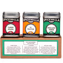 Three Spicewalla spice tins labeled 'Carne Asada', 'Al Pastor', and 'Pescado Verde' on a cardboard stand.