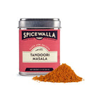 A pink Spicewalla Tandoori Masala tin with white and black text and a silver lid sits next to a small pile of orange-red Indian spice blend, ideal for grilled chicken.