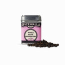 A tin of Spicewalla Whole Black Peppercorns, with a pink and black label, sits beside a small pile of peppercorns on a white background, ready to add bold aroma and flavor to your dishes.
