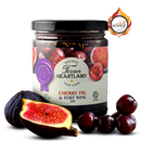 A jar of Texan Heartland Cherry Fig & Port Wine Jam sits with fresh figs and cherries, featuring a Scovie Award logo. This gourmet jam by Texan Heartland is ideal for artisan cheese pairings or an elegant spread addition.