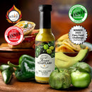 A bottle of Texan Heartland Hill Country Verde Hot Sauce, made with roasted poblanos, is surrounded by fresh green peppers, tomatillos, tacos, and award badges—including a Winner 2025 Fiery Food Challenge label.
