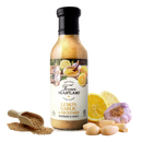 A bottle of Texan Heartland Lemon, Garlic & Mustard Marinade & Sauce sits beside mustard seeds, garlic cloves, a halved lemon, and a garlic bulb to showcase this flavorful and versatile product from Texan Heartland.
