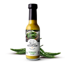 A bottle of Texan Heartland Serrano Sunfire Hot Sauce by Texan Heartland sits among green serrano peppers, its label showing a close-up of the peppers and product info on a white background.