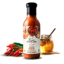A bottle of Texan Heartland Texas Pequin & Honey Mop Sauce & Marinade stands between red chili peppers and a jar of honey with a dipper, set against a white background. Perfect as a flavorful honey marinade.
