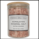 A clear glass jar with a wooden lid contains Texas Salt Co. Himalayan Pink Extra Coarse Salt, Net Wt 15oz (425g), filled with large, mineral-rich pink salt crystals.
