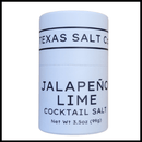 Texas Salt Co. Jalapeño Lime Cocktail Salt comes in a white cylindrical container, featuring bold black lettering on a clean background. This spicy citrus rim salt is ideal for margaritas. Net Wt 3.5oz (99g).
