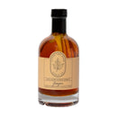 Under The Bark Syrup Co Ginger Maple Syrup comes in a glass bottle with a beige label featuring a leaf. Infused with ginger root, visible inside, this amber syrup offers a unique ginger maple syrup experience.