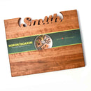 The Words With Boards Large Personalized Cutting Board (12.5" x 16") by Words with Boards, LLC features "Smith" cut out at the top, a green paper band around the center, and "April 6, 2018" engraved in the lower right corner.