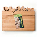 The Words With Boards Personalized Cutting Board Small 9.5" x 12.5" by Words with Boards, LLC features “My Hero” cut out at the top and a green Ford’s Boards tag attached with twine, making it a unique hardwood kitchen gift against a white background.