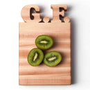 The Words With Boards Gluten Free Personalized Cutting Board (6 1/4" x 9 1/2") by Words with Boards, LLC features "G.F." on top, shown with three halved green kiwis—ideal for a celiac-safe kitchen.