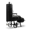 The Yoder Smokers Durango 20 Offset Smoker by Yoder Smokers features a black metal build, large capacity, vertical smoking chamber, horizontal cooking chamber, wheels for mobility, and a small white bucket hanging from the vertical chamber.