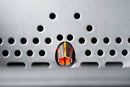 Close-up of a metal surface with rows of circular holes, an orange glow shining through one—evoking the direct-flame grilling of a Yoder Smokers YS480S Competition Pellet Grill with Stainless Steel Shelves for an abstract, industrial effect.