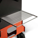 A close-up of the wire shelves attached to the side of a Yoder Smokers YS640S Competition Pellet Grill, a black and orange grill with wheels, designed for authentic wood-fired flavor.