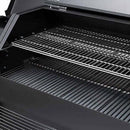 A close-up of the Yoder Smokers YS640S Competition Pellet Grill with Wire Shelves shows two chrome cooking grates and a spacious interior, ready for wood-fired flavor. The open lid highlights the grill's clean design by Yoder Smokers.