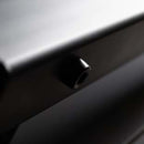 Close-up of a black knob on the sleek, dark metallic surface of the Yoder Smokers YS640S Competition Pellet Grill with Wire Shelves, highlighted by soft lighting that hints at authentic wood-fired flavor.