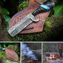 The Texan Knives Custom Handmade Bull Knife – Fall Damascus Steel Edition features a patterned blade and blue-black handle atop a leather sheath; additional images show the sheath, a campfire, and camping scenes in the woods.