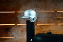 A silver Baseball Batting Helmet BBQ Chimney Cap by Pimp My Grill sitting atop a smokestack on a grill.