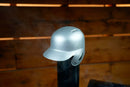 A silver Baseball Batting Helmet BBQ Chimney Cap - Silver | Pimp My Grill® sits on a vent pipe with wisps of smoke.