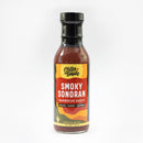 A 14.5 oz (411g) bottle of Chiles and Smoke Smoky Sonoran BBQ Sauce, featuring a red and yellow label with the words "Fruity, Tangy, Savory." This bold and smoky barbecue sauce from Chiles and Smoke is perfect for grilling.