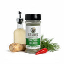 A bottle of B.T. Leigh’s Zesty Dill Lemongrass Seasoning next to a small carafe of oil, a piece of horseradish, a sprig of fresh dill, and a red chili pepper.
