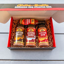 The Chiles and Smoke Sonoran BBQ Starter Box showcases three spice jars—Canyon Crust, Sedona Sand, and Scorching Sun—alongside a bottle of Smoky Chipotle sauce, all attractively packed to deliver bold Sonoran Desert flavor to your live fire cooking adventures.