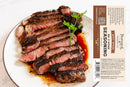 A sliced, grilled steak is served on a white plate with herbs, accompanied by a brown and white Powerful Pepper Steak Seasoning No. 5 label from Powerful Pepper Company displaying ingredients and nutrition facts. This gourmet blend highlights the rich depth of black garlic, elevating each bite with bold layers of flavor.