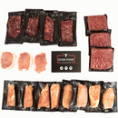 The Dude Food Essentials Meat Box by Dude Food is displayed on a white background, featuring vacuum-sealed ground beef, flat iron steaks, pork chops, and boneless chicken breasts arranged around a Dude Food card.