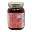A small glass jar with a gold lid contains Powerful Pepper Company’s “Powerful Pepper Strawberry Death Spiral Chili Jam,” a dark red spread. The label lists strawberries, pectin, sugar, citric acid, and fiery Death Spiral Peppers among the ingredients—making this a truly spicy jam. “Georgia Grown” is also printed alongside distributor information.