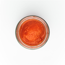 A top-down view of an open glass jar of Taycte Famiglia Crispino Grilled Vegetable Pasta Sauce — Roasted Italian Veggie Sugo, its smooth, vibrant red contents on display against a white background.