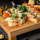 A wooden platter displays assorted sushi rolls, shrimp nigiri, avocado slices, black caviar, SALTOPIA Wasabi Salt: WAS-AB-HAPPENIN by SALTOPIA Infused Sea Salts, pickled ginger, and garnish—a perfect sushi companion for any occasion.