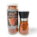 Two clear SALTOPIA Infused Sea Salts containers of the BBQ Blend: HE MAN are shown. One is a tall jar with grilled meat on the label; the other is a smaller black-topped smoky BBQ grinder. Both contain reddish salt.