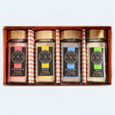 The Spice Wheel Mocktail Sugar Gift Set includes four glass jars of flavored sugars—strawberry, lemon, blueberry, and lime—arranged in an orange box with patterned sides. Each jar in this gourmet gift set by Spice Wheel features a colorful label and matching lid, perfect for enhancing tea, baking, mocktails, or cocktails.