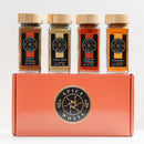 Four spice jars labeled Garam Masala, Coriander, Kashmiri Powder, and Turmeric are arranged on top of the Spice Wheel Indian Spice Gift Set box by Spice Wheel, which features a circular logo in the center—creating a vibrant collection ideal for authentic Indian cooking.