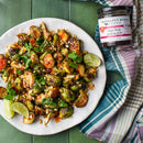 A plate of roasted Brussels sprouts with herbs, peanuts, and lime rests by a jar of Terrapin Ridge Farms Thai Chili Guava Jam—a sweet and spicy Terrapin Ridge Farms condiment ideal for charcuterie boards.
